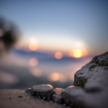 blurry photo of a rock with a sunset in the background and a blurry image of a body of water