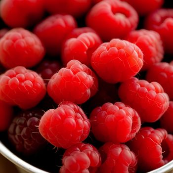 bowl of raspberries is shown with a few more raspberries in the background to the side