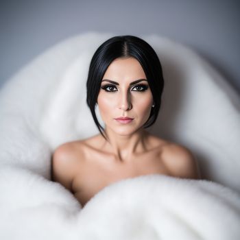 woman with black hair and makeup is sitting in a white chair with a fur blanket on her head