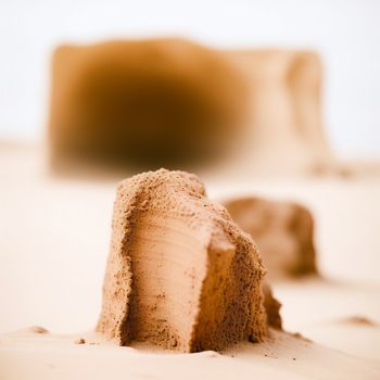 piece of cake that is on a table with a blurry background of a desert area with a small mound of dirt