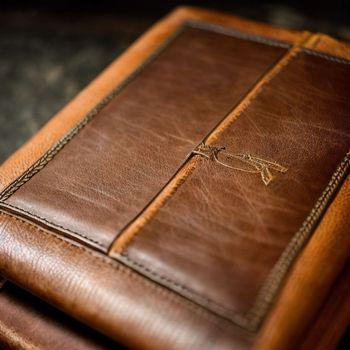 close up of a brown leather case on a black table with a knife sticking out of it