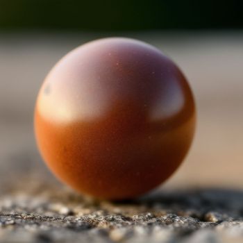 red ball sitting on top of a cement floor next to a wall