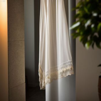 white dress hanging in a room next to a potted plant